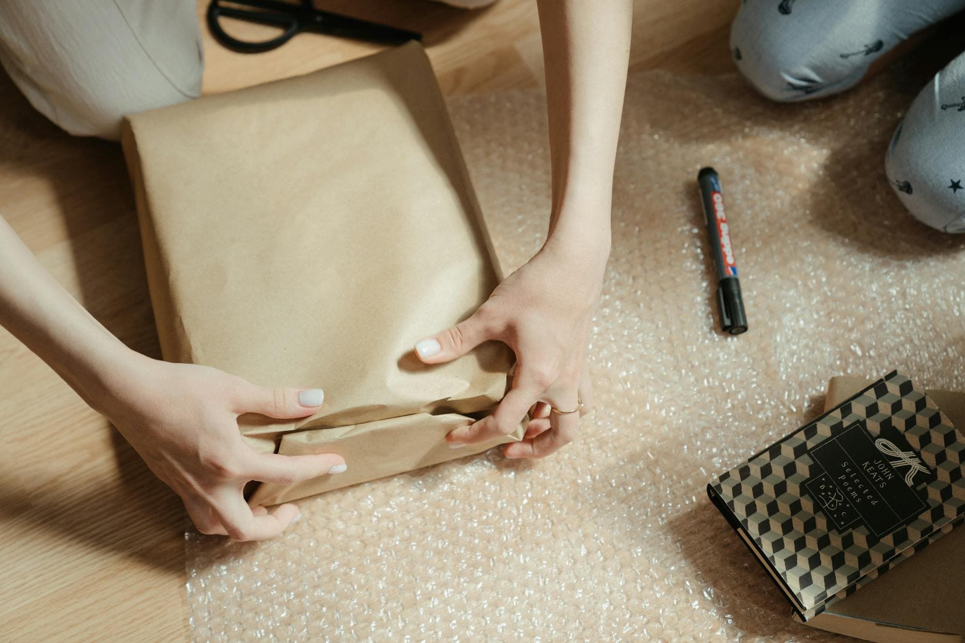 Hands wrapping a brown craft paper package, ready to ship from a new SitesPlaced store